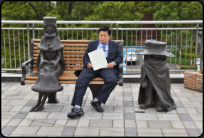 Müder Japaner zwischen den Statuen von Tetsuro and Maetel aus "Galaxy Express 999"